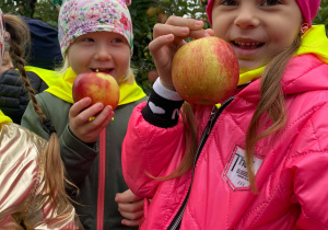 dziewczynki pokazują zerwane jabłka
